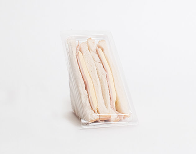ham sandwich cut into halves in plastic container, sat in the middle of a plain white background